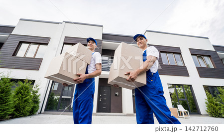 Two removal company workers unloading boxes into new customer's home Two removal company workers unloading boxes into new customer's home 142712760