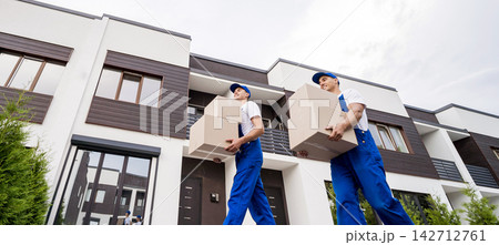 Two removal company workers unloading boxes into new customer's home 142712761
