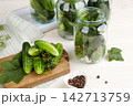 Cucumbers are laid out in jars along with dill and spices on the kitchen table. T  142713759
