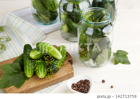 Cucumbers are laid out in jars along with dill and spices on the kitchen table. T Cucumbers are laid out in jars along with dill and spices on the kitchen table. T 142713759