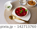 Traditional beetroot borscht served in a white ceramic bowl with fresh basil, dill sauce  142713760