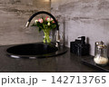A black circular sink is placed in a kitchen with gray walls.  142713765