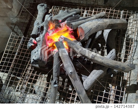 バーベキューグリルの網の上で赤々と燃える炭火 キャンプのアウトドア火起こし バーベキューグリルの網の上で赤々と燃える炭火 キャンプのアウトドア火起こし 142714387
