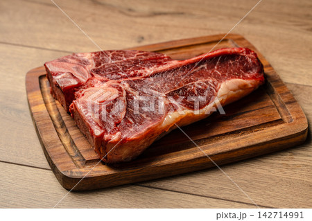 Raw T Bone Steak on Rustic Wooden Board 142714991
