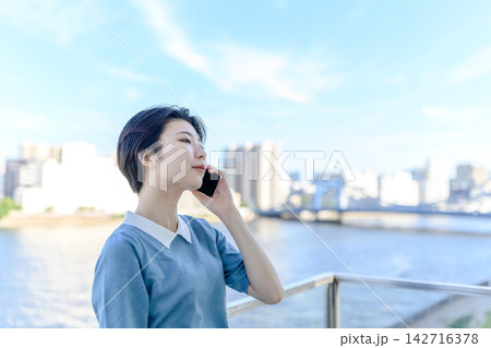 女性、スマホで通話しながら空を見上げる 142716378