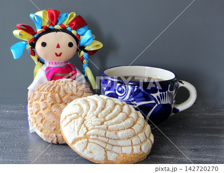Talavera cup with hot coffee and Mexican sweet bread baked for a breakfast wiht a traditional doll 142720270