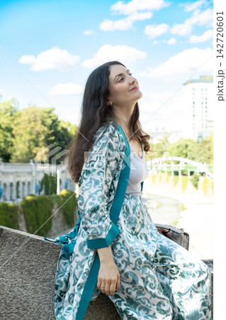 Beautiful adult brunette female sitting outdoors in city park Beautiful adult brunette female sitting outdoors in city park 142720601