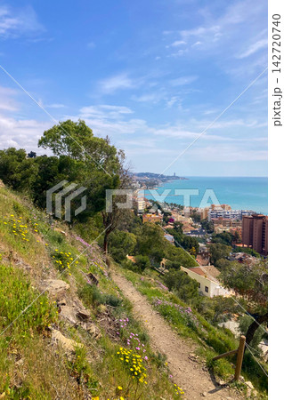 A winding hiking path leads to the historic fortress with walkable stone walls and sweeping panoramic city and coastal views in Malaga, Spain A winding hiking path leads to the historic fortress with walkable stone walls and sweeping panoramic city and coastal views in Malaga, Spain 142720740