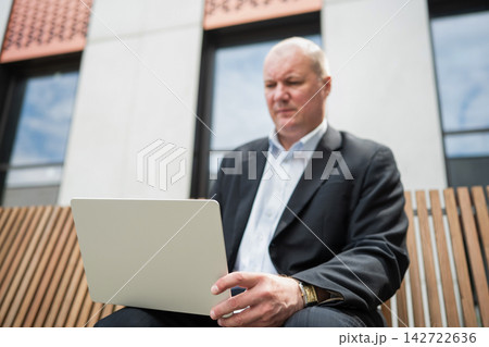Businessman working on laptop outdoors Businessman working on laptop outdoors 142722636