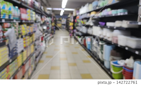 Blurred interior view of a supermarket aisle with stocked shelves of household goods 142722761