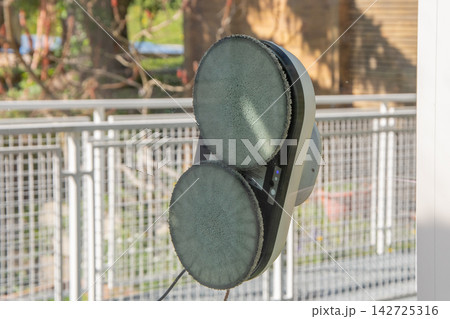Robotic window cleaning device attached to glass outdoors 142725316