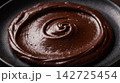 Luxurious melted cocoa texture displaying an elegant glossy swirl of dark chocolate ganache. 142725454