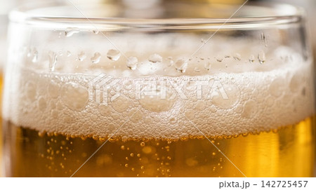 Extreme close up texture of a refreshing cold pint glass highlighting rising carbonation and amber liquid glow. Extreme close up texture of a refreshing cold pint glass highlighting rising carbonation and amber liquid glow. 142725457