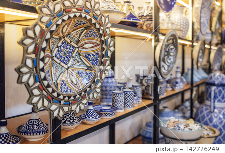 Colorful ceramic plates and decorative pottery displayed on shelves, showcasing intricate patterns and craftsmanship in a vibrant artisan shop environment 142726249