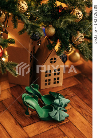 New Year decorations and beautiful green female high-heeled shoes under decorated Christmas tree. 142726289