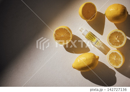 Yellow lemons and a glass bottle of essential oil arranged on a light surface, showcasing fresh citrus fruits and natural skincare elements in a minimalistic setting Yellow lemons and a glass bottle of essential oil arranged on a light surface, showcasing fresh citrus fruits and natural skincare elements in a minimalistic setting 142727136