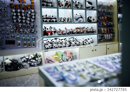 Display of assorted panda-themed merchandise including plush toys, keychains, and stationery items in a brightly lit retail store setting 142727785