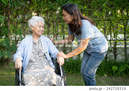 Caregiver help Asian elderly woman disability patient sitting on wheelchair in park. 142728319