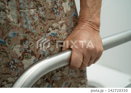 Asian elderly woman patient use toilet support rail in bathroom. Asian elderly woman patient use toilet support rail in bathroom. 142728350