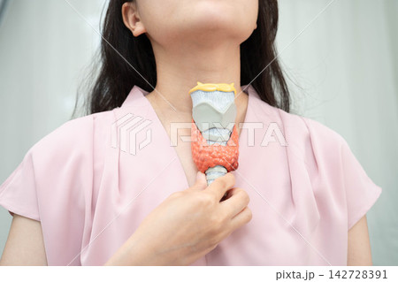 Hyperthyroidism, Overactive Thyroid, Thyroid Lymphoma, Asian woman with thyroid gland human anatomy model. Hyperthyroidism, Overactive Thyroid, Thyroid Lymphoma, Asian woman with thyroid gland human anatomy model. 142728391