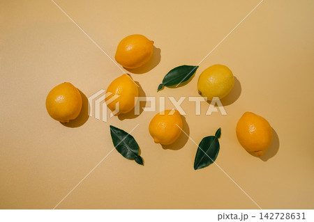 Fresh lemons and green leaves arranged on warm yellow background, minimalist citrus still life with natural sunlight and copy space Fresh lemons and green leaves arranged on warm yellow background, minimalist citrus still life with natural sunlight and copy space 142728631