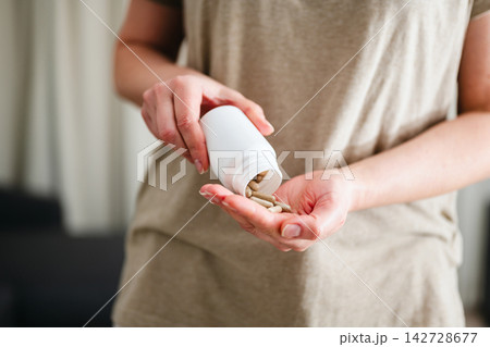 Woman pouring a pile of pills, capsules from a bottle in hand. Prescription medication, treatment sickness concept Woman pouring a pile of pills, capsules from a bottle in hand. Prescription medication, treatment sickness concept 142728677