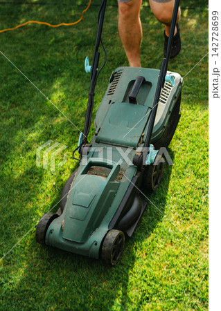 Person mowing lawn in backyard garden, home lawn care and summer yard maintenance 142728699