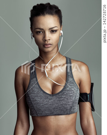 Studio, portrait and athlete woman with earphones for streaming music, audio podcast or fitness playlist. Grey background, exercise and person for cardio workout, sports or physical training Studio, portrait and athlete woman with earphones for streaming music, audio podcast or fitness playlist. Grey background, exercise and person for cardio workout, sports or physical training 142728716