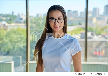 Young smiling female student in eyeglasses looking directly at camera Young smiling female student in eyeglasses looking directly at camera 142728854