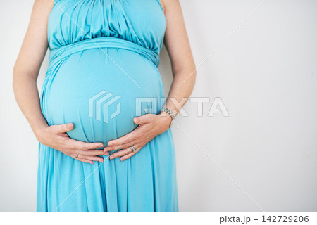 Pregnant, woman and hands on stomach in studio for family, healthy mama with love for young. Female person, holding or belly for pregnancy with white background for wellness, gratitude in Chicago Pregnant, woman and hands on stomach in studio for family, healthy mama with love for young. Female person, holding or belly for pregnancy with white background for wellness, gratitude in Chicago 142729206