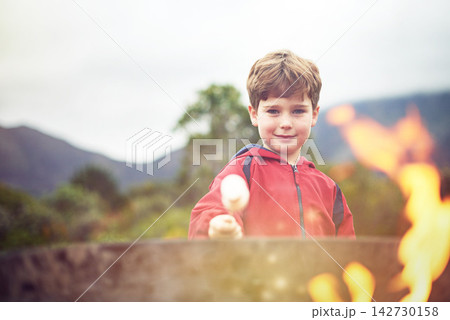 Outdoors, fire and boy in portrait with marshmallow for cooking on flame with happiness. Roast, smile and camping with sweets for scenic mountain in winter morning at campsite in Switzerland. Outdoors, fire and boy in portrait with marshmallow for cooking on flame with happiness. Roast, smile and camping with sweets for scenic mountain in winter morning at campsite in Switzerland. 142730158