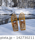 classic wooden snowshoes (Bear Paw) on a stream shore, winter scenery in Colorado 142730211