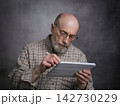 casual portrait of bald, bearded senior man working on a digital tablet with electronic pencil 142730229