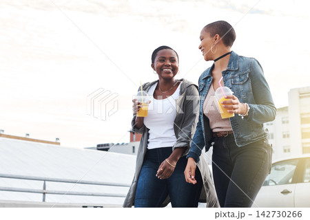 Orange juice, women and friends in city, walking and conversation with happiness, bonding together and smile. People, outdoor and girls with drinks, funny and laughing for joke, cheerful and joyful 142730266