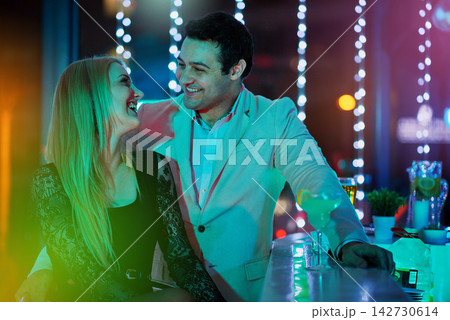 Couple, talking and relax at bar in club, bonding together and alcohol for new year celebration. Happy people, party and speaking at social event, communication and fun in relationship at night Couple, talking and relax at bar in club, bonding together and alcohol for new year celebration. Happy people, party and speaking at social event, communication and fun in relationship at night 142730614