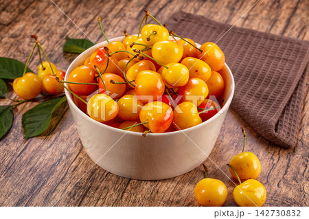 Fresh sweet yellow cherries in white bowl on rustic wood background 142730832