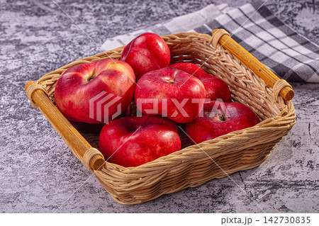 Red apples in woven basket on textured surface with checkered cloth 142730835