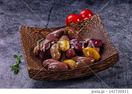 Assorted olives in rustic wooden bowl with cherry tomatoes and fresh herb on dark textured background Assorted olives in rustic wooden bowl with cherry tomatoes and fresh herb on dark textured background 142730911