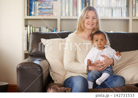 Mother, girl and hug for adoption on sofa for quality family bonding time together in living room. Family, diversity and woman with smile for foster care at home with love, support and acceptance 142731533