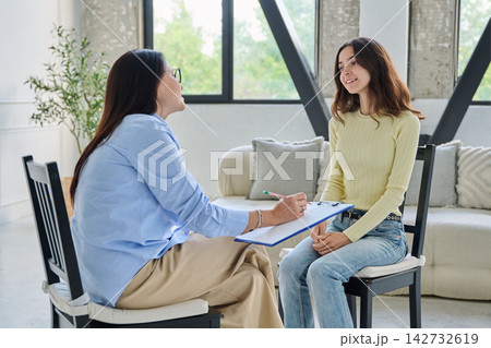Young smiling woman talking to female psychologist during therapy session Young smiling woman talking to female psychologist during therapy session 142732619