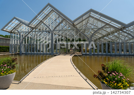 Walkway over a reflection pool to a modern glass conservatory 142734307