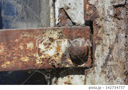 Rusty metal hinge with flaking paint and corrosion 142734737