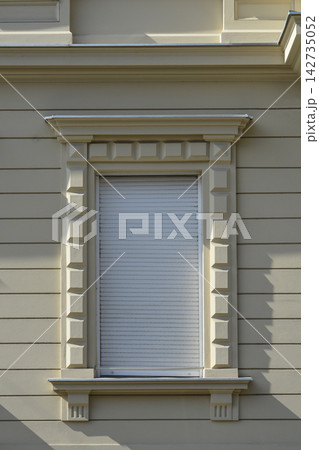 Classic Window with Decorative Stone Frame and Closed Shutter 142735052