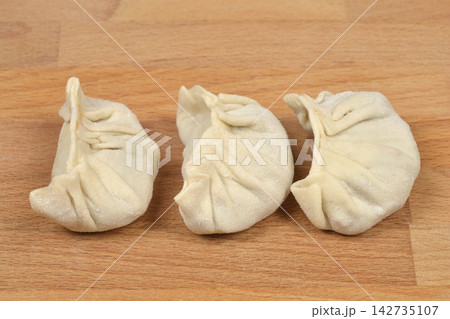 Three pleated dumplings on a wooden board Three pleated dumplings on a wooden board 142735107