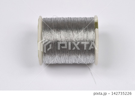 Spool of silver metallic sewing thread Spool of silver metallic sewing thread 142735226
