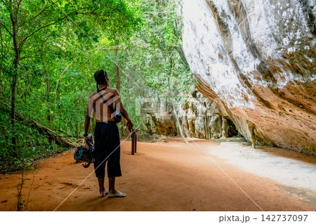 Explorer walking along dirt path beside rock formation Explorer walking along dirt path beside rock formation 142737097