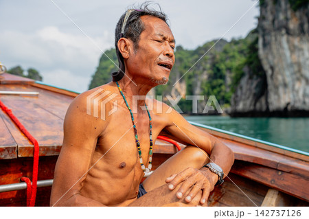 Thai senior man relaxing on traditional longtail boat Thai senior man relaxing on traditional longtail boat 142737126