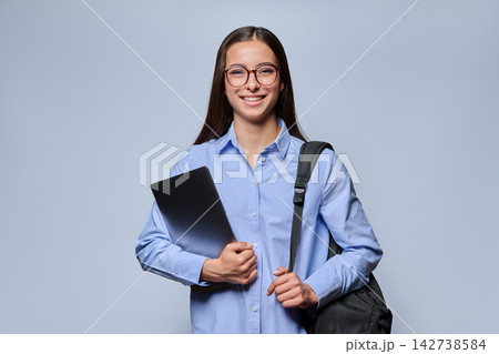 Smiling young woman student in glasses holding laptop and backpack studio shot Smiling young woman student in glasses holding laptop and backpack studio shot 142738584