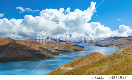 Serene Highland Lake Surrounded by Rolling Hills Under a Blue Sky with White Clouds in Tibet Serene Highland Lake Surrounded by Rolling Hills Under a Blue Sky with White Clouds in Tibet 142739184