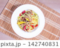 Bowl of salad with green papaya, meat, and spices on a bamboo mat 142740831